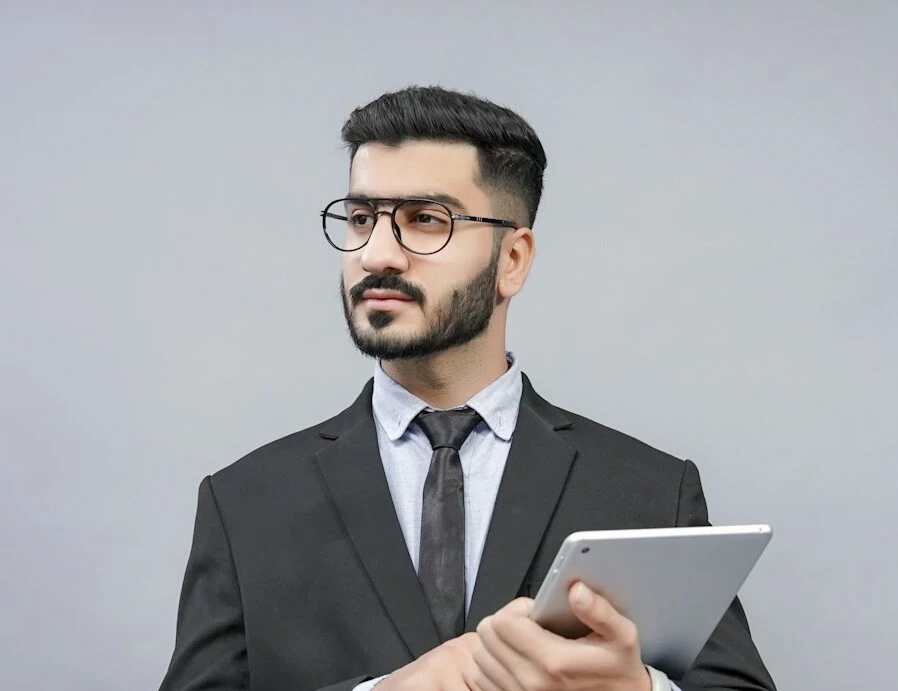 Un chico joven con gafas y traje formal y barba miró hacia un lado.