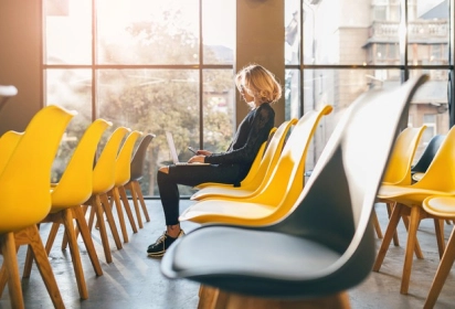 empty glass room with yellow chairs and one person sitting