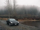 Car parked by a foggy lakeside with trees