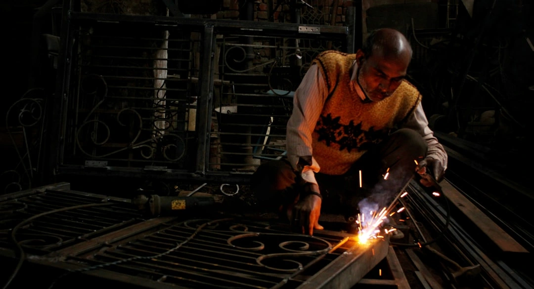 Person welding metal in a dark workshop environment.