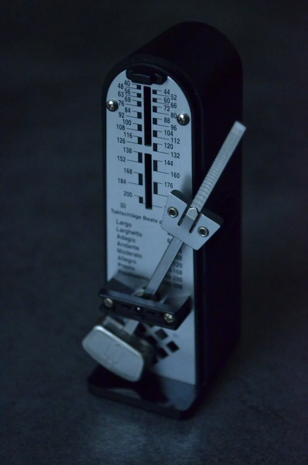 Black metronome with a white scale and adjustable arm.