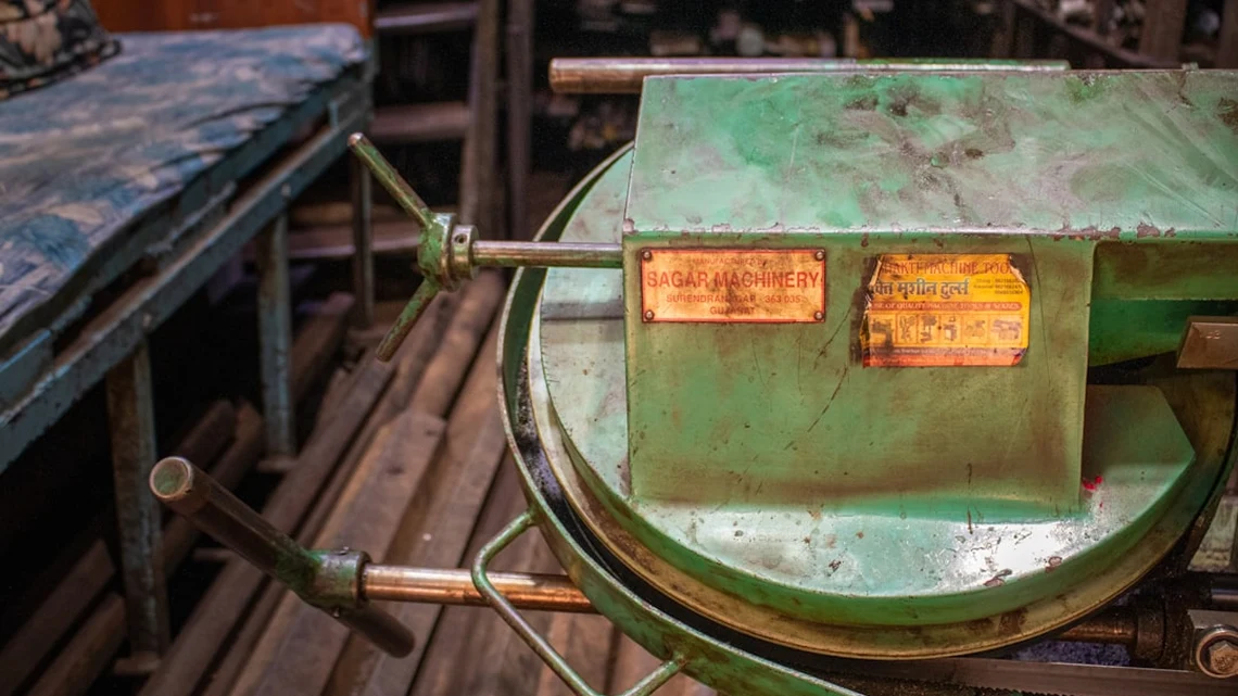 Green machinery with labels, located on wooden floor.