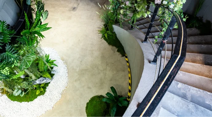 Concrete Garden residential courtyard design in Berlin featuring a curved staircase, sandy path, and lush green plants