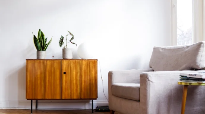 The White Residence minimalist interior design in Poznan featuring a wooden sideboard, armchair, and indoor plants